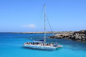 catamaran in turquiose water against rocky shore