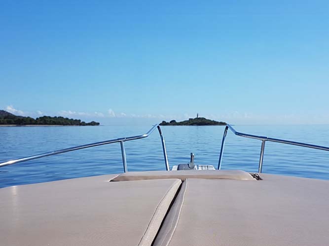 Blick über Bootsbug auf ruhiges Wasser und Insel Alcanada