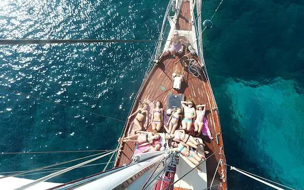 people sunbathing on deck of a sailing yacht
